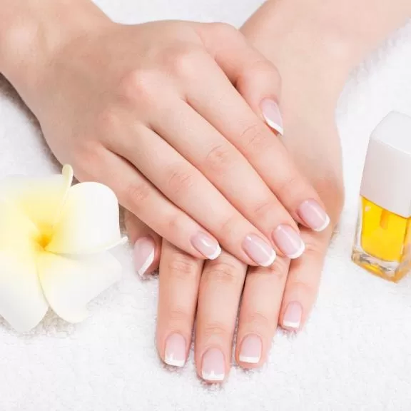 Manicured hands resting on a nail-bar surface